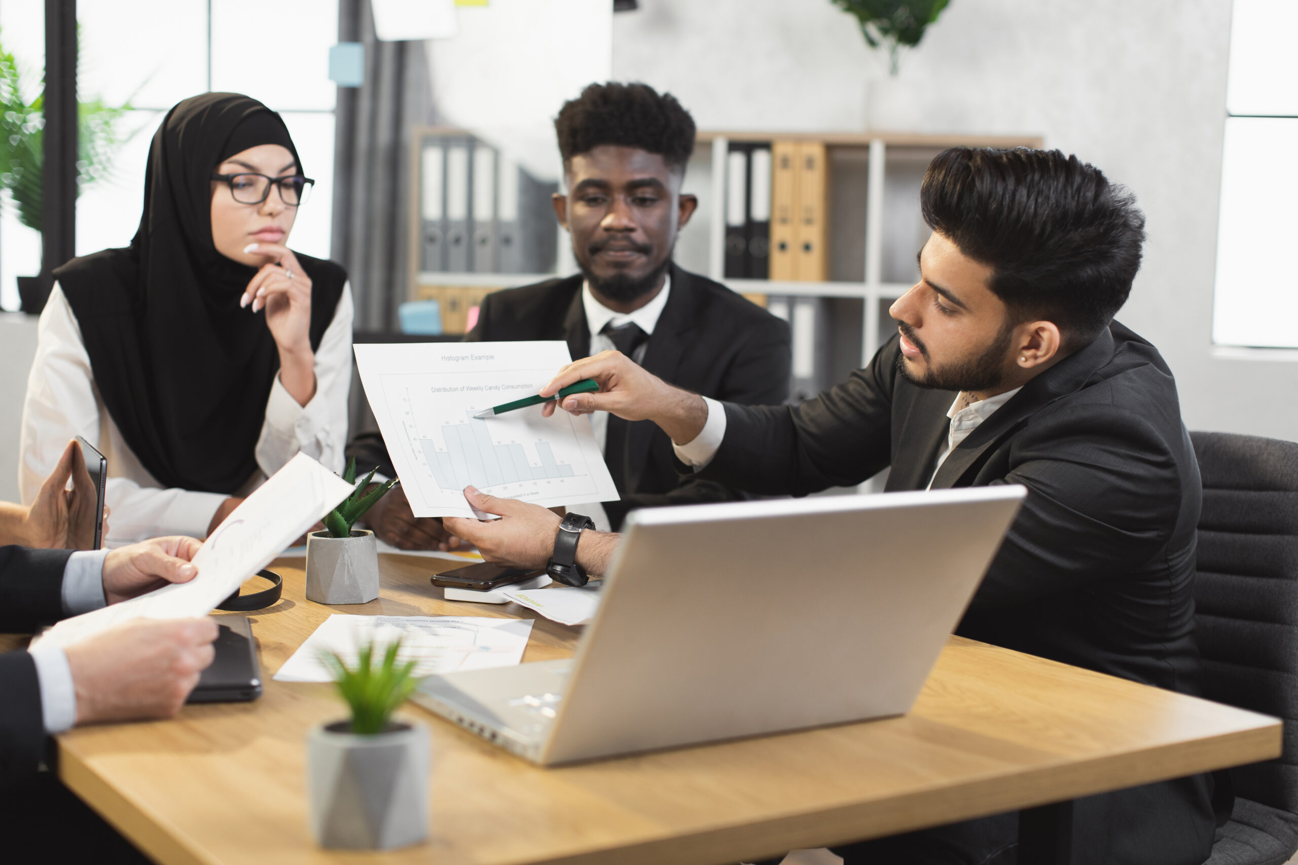 Malaysian financial consultants discussing grant application documents in a boardroom